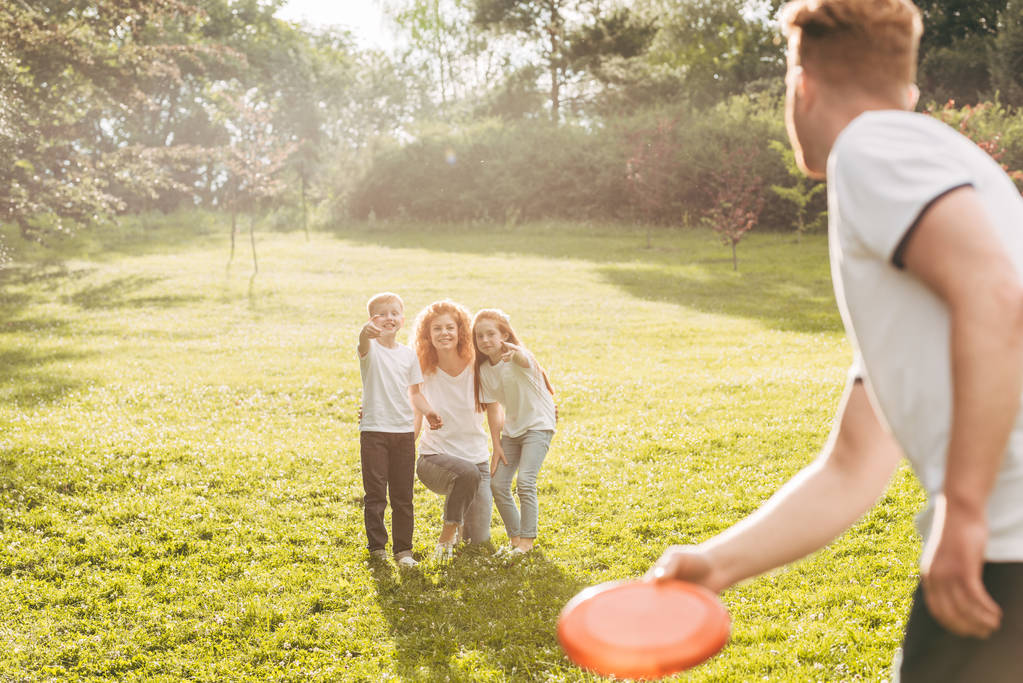 família ruiva feliz jogando com disco voador no parque
 - Foto, Imagem