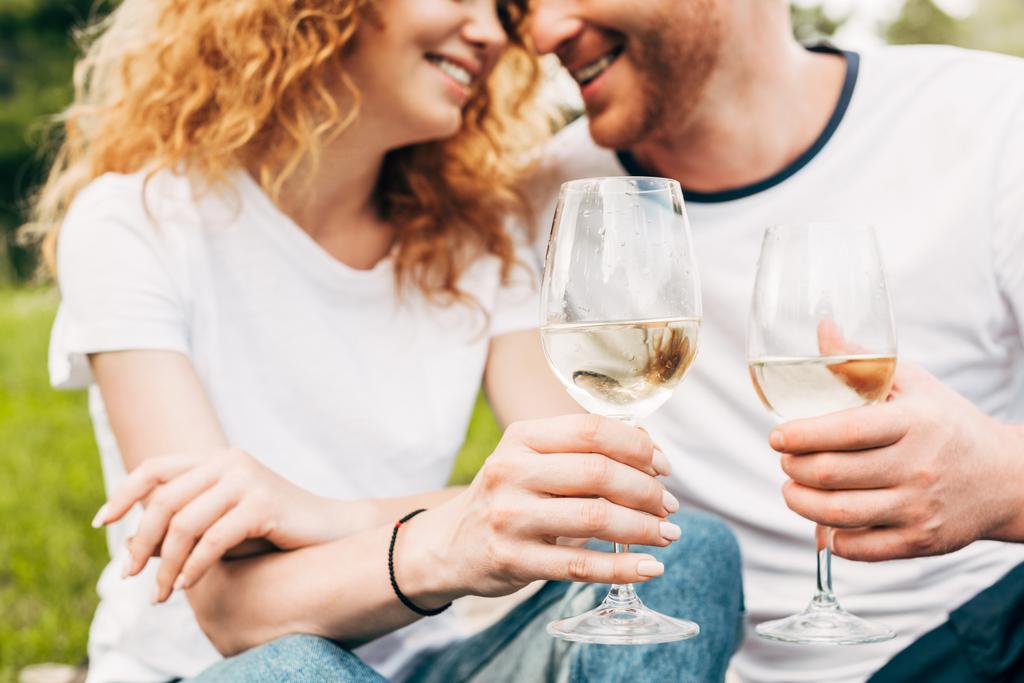 公園内のワインのグラスを持って幸せなカップルのショットをトリミング - 写真・画像