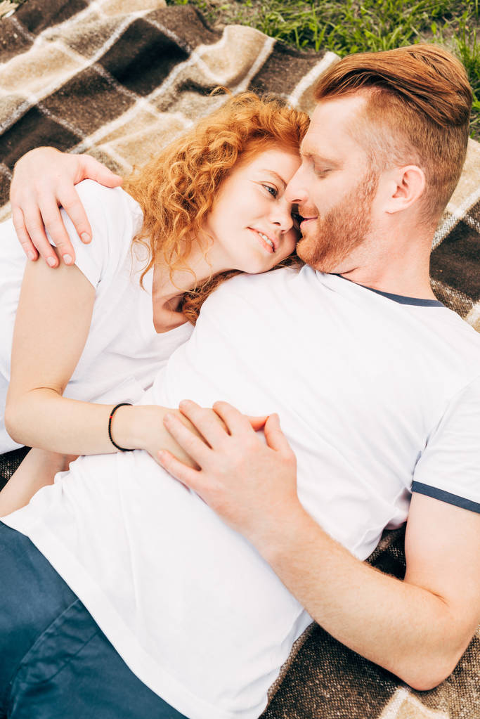 vue grand angle de jeune couple heureux tenant la main et couché ensemble sur plaid au pique-nique
 - Photo, image