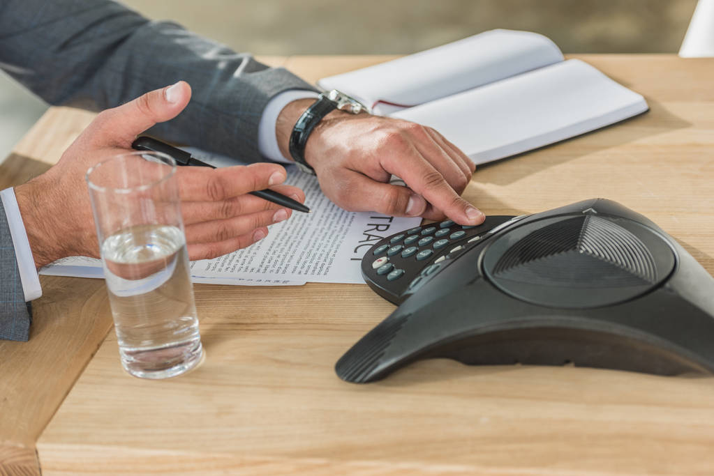 обрізаний знімок бізнесмена, використовуючи конференц-телефон на столі в офісі
 - Фото, зображення