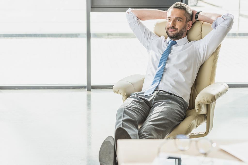 homem de negócios bonito relaxando em poltrona de luxo no escritório moderno
 - Foto, Imagem