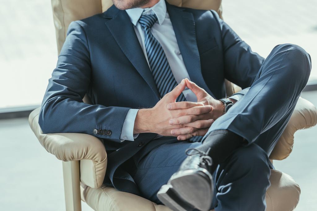 обрезанный снимок бизнесмена, расслабляющегося на роскошном кресле в современном офисе
 - Фото, изображение