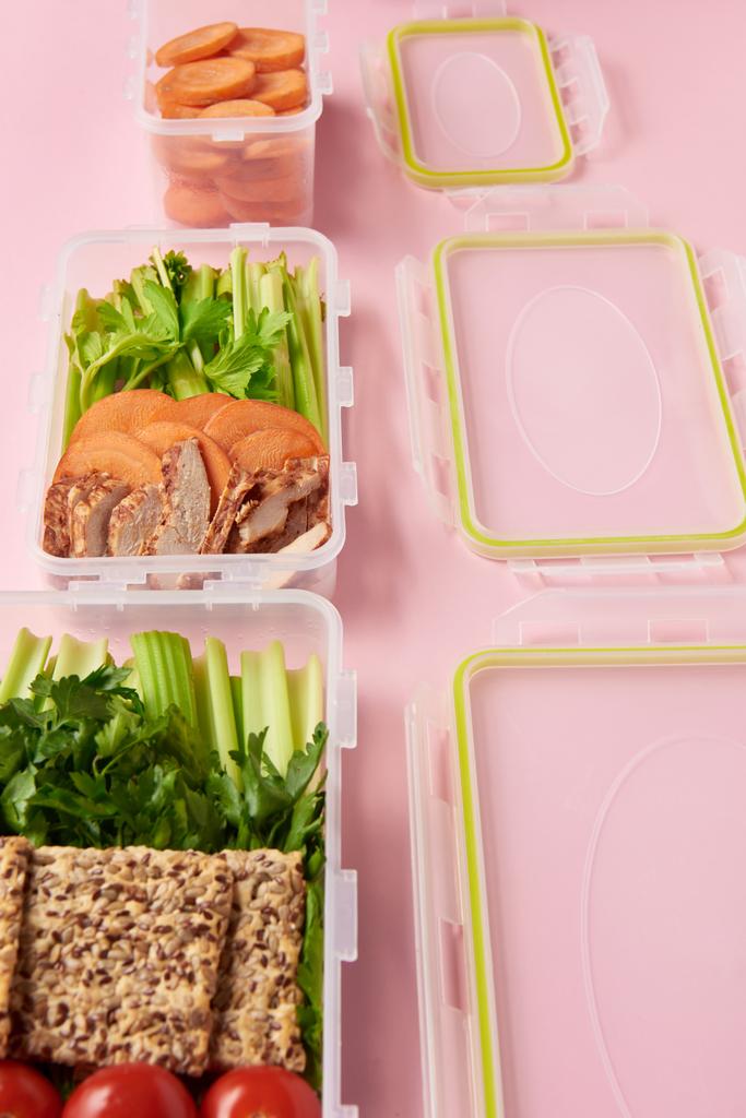 κλείνω πάνω θέα υγιή φρέσκων τροφίμων που διοργανώνονται σε δοχεία τροφίμων σε ροζ φόντο - Φωτογραφία, εικόνα