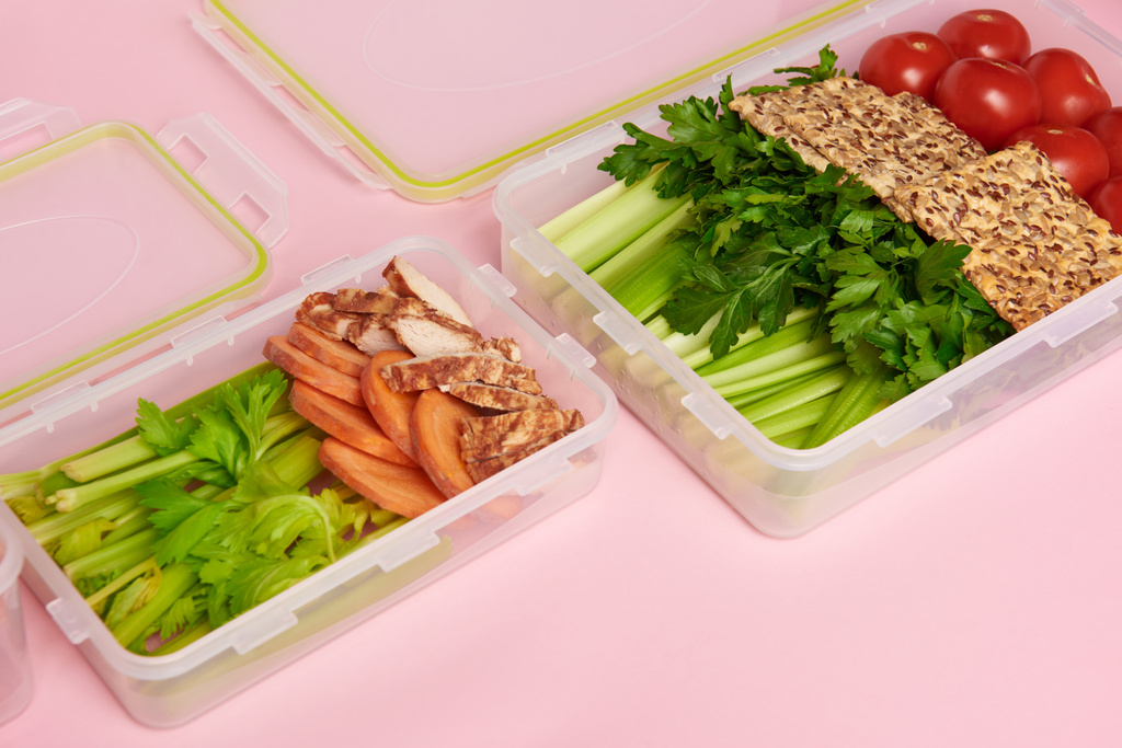 vista de cerca de verduras y galletas saludables dispuestas en recipientes de alimentos sobre fondo rosa
 - Foto, Imagen