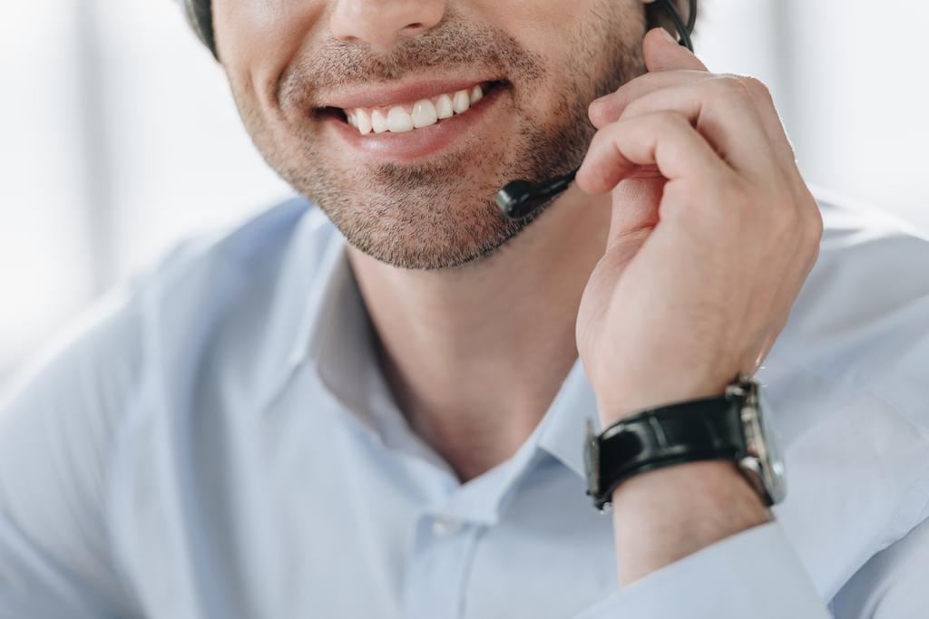 abgeschnittene Aufnahme eines lächelnden Support-Hotline-Mitarbeiters mit Mikrofon - Foto, Bild