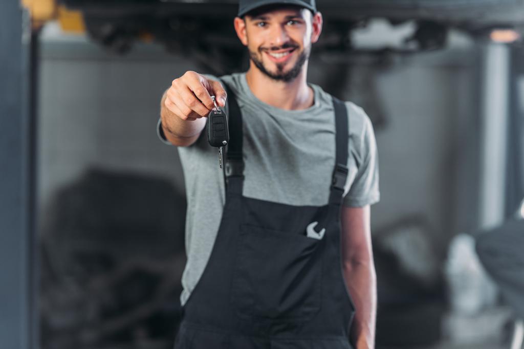 usmívající se mechanika drží klíče od auta v automatické opravna - Fotografie, Obrázek