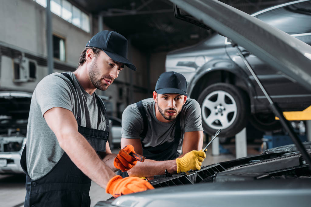 професійні ручні працівники ремонтують автомобіль в механічному магазині
 - Фото, зображення