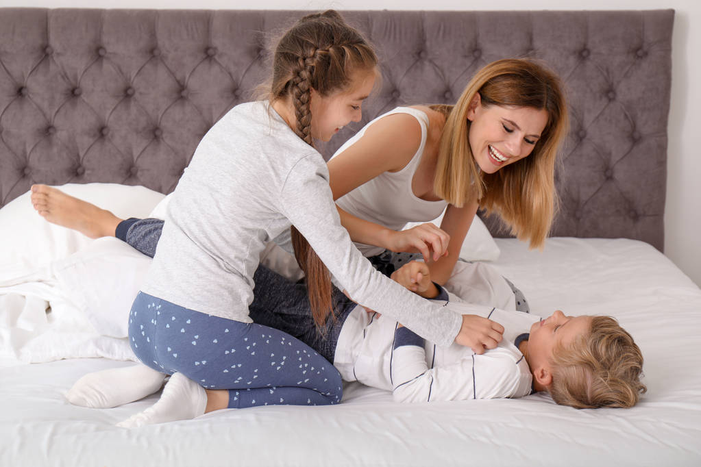 Donna che gioca con i bambini in camera da letto. Famiglia felice
 - Foto, immagini