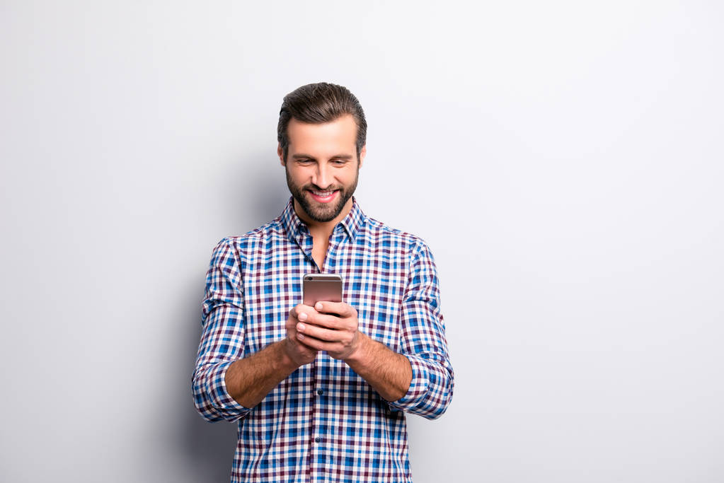 Portrait von aufgeregten zufrieden mit zahm strahlend glänzendes Lächeln mit Ruhepause mit Smartphone für das Senden von SMS isoliert auf grauem Hintergrund copy-sapce - Foto, Bild