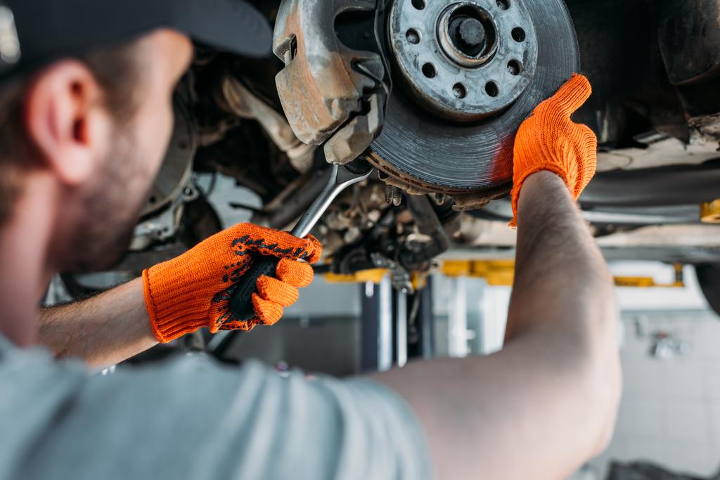 enfoque selectivo del trabajador profesional de reparación de coches sin rueda en el taller mecánico
 - Foto, imagen