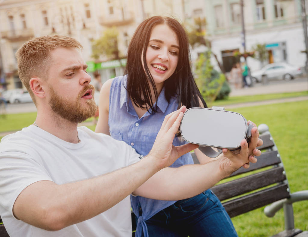 Giovane coppia caucasica gioca un gioco utilizzando occhiali di realtà virtuale per strada. Auricolare VR
. - Foto, immagini