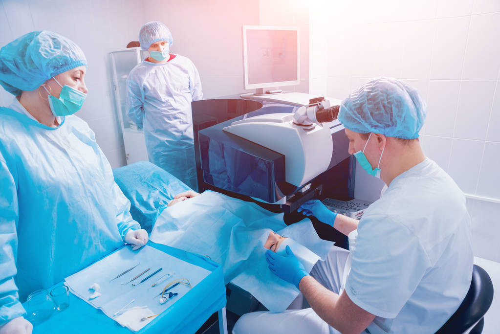 paziente e team di chirurghi in sala operatoria durante l'intervento oftalmico
 - Foto, immagini