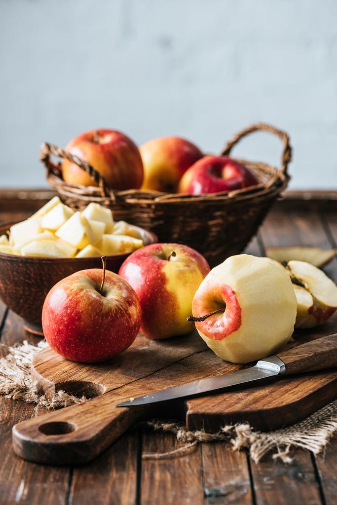 Close-up van gezonde, gepelde en gesneden appelen op snijplank op donkere houten oppervlak - Foto, afbeelding