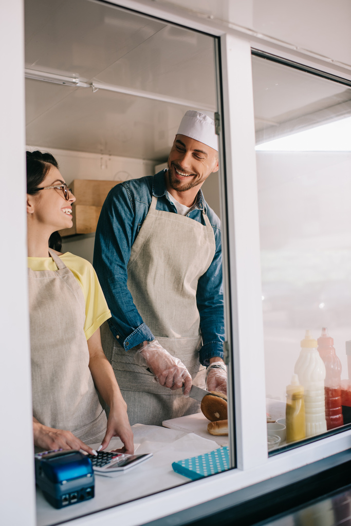 молодий чоловік і жінка посміхаються один одному, працюючи разом у харчовій машині
 - Фото, зображення