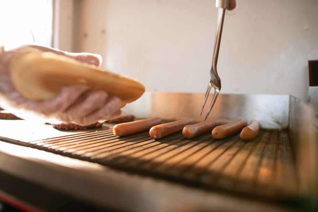 обрізане зображення шеф-кухаря, який готує собаку у харчовій вантажівці та приймає ковбасу
 - Фото, зображення