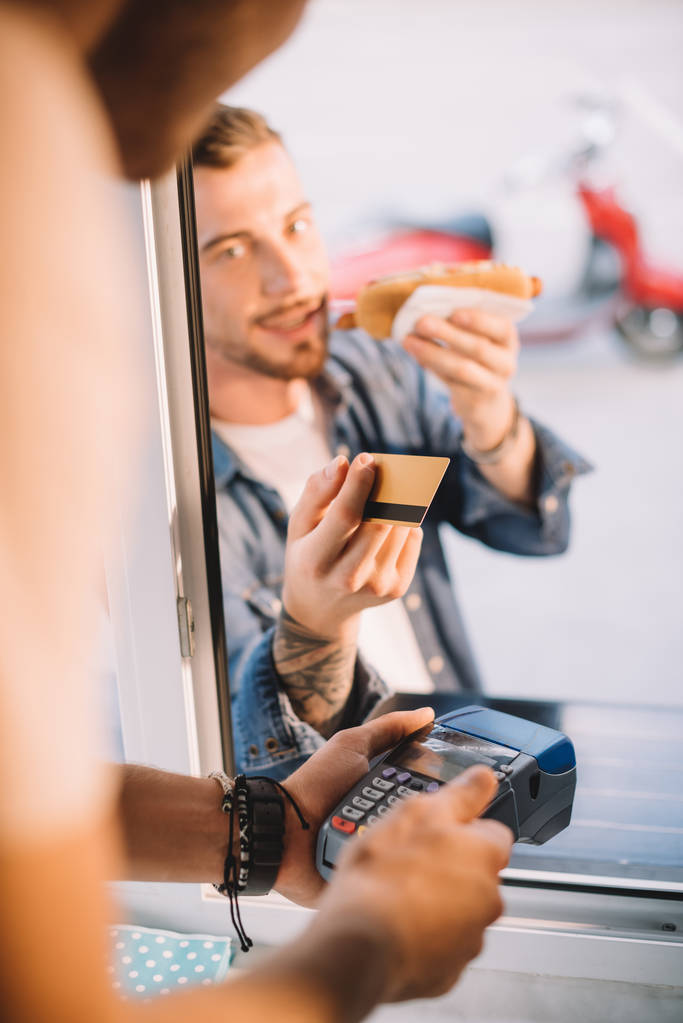 περικομμένη εικόνα του πελάτη δίνοντας πιστωτική κάρτα ως σεφ σε φορτηγό τροφίμων - Φωτογραφία, εικόνα