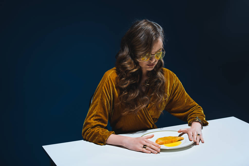 luxus minőségű ruházatot, asztalnál ült hús péksütemények lemez kék hátteret a nő portréja - Fotó, kép