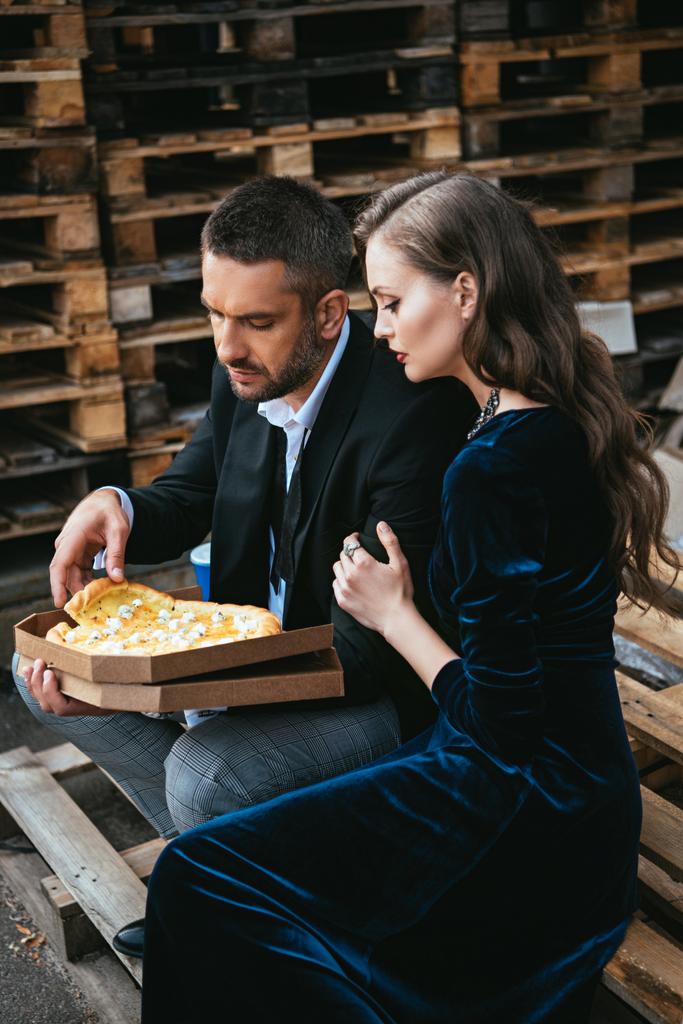 vista lateral do casal elegante com pizza de queijo italiano descansando na rua
 - Foto, Imagem