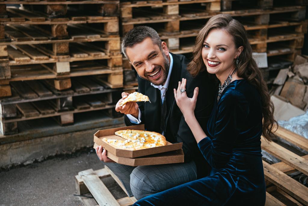vista laterale di felice coppia elegante con pizza al formaggio italiano poggiata sulla strada
 - Foto, immagini
