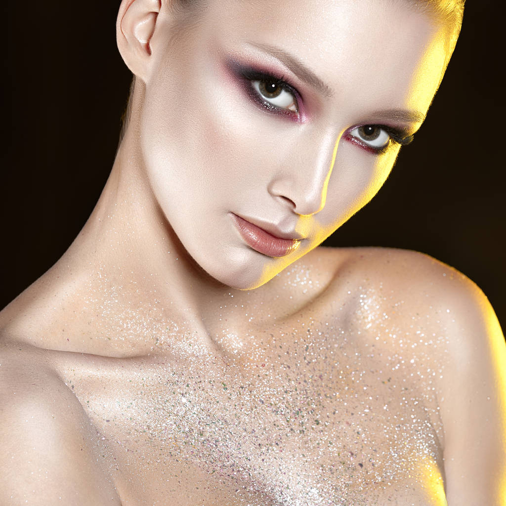Young beautiful girl with pink make-up and glitter in decolletage zone. Beauty close-up portrait - Photo, Image