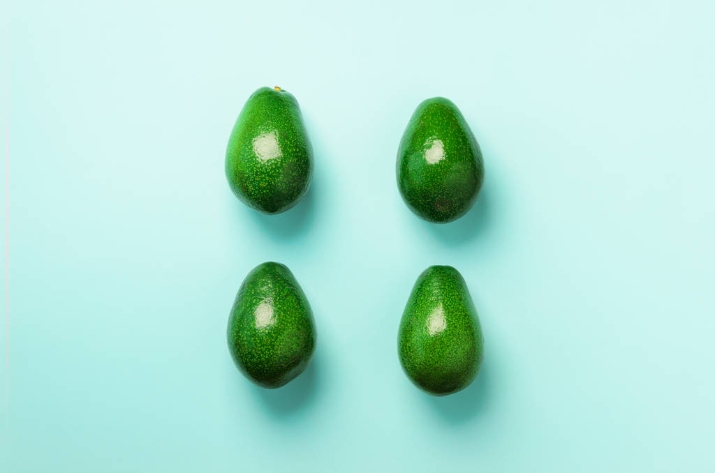 Modello avocado verde su sfondo blu. Vista dall'alto. Pop art design, concetto creativo di cibo estivo. Avocado organico in stile flat lay minimale
. - Foto, immagini