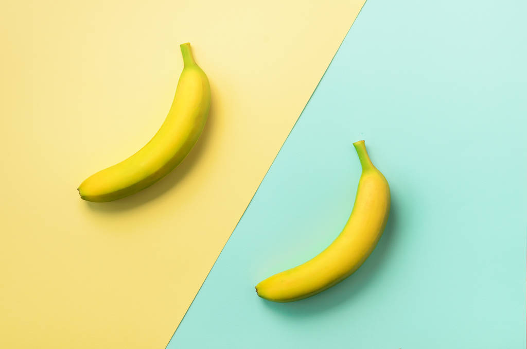 Μπανάνες πάνω από μπλε και κίτρινο βάθους. Πολύχρωμα φρούτα μοτίβο με αντίγραφο χώρου. Το Top view. Pop art design, δημιουργικό καλοκαίρι έννοια. Πανό. Μπανάνα σε minimal ύφος για επίπεδη lay. - Φωτογραφία, εικόνα
