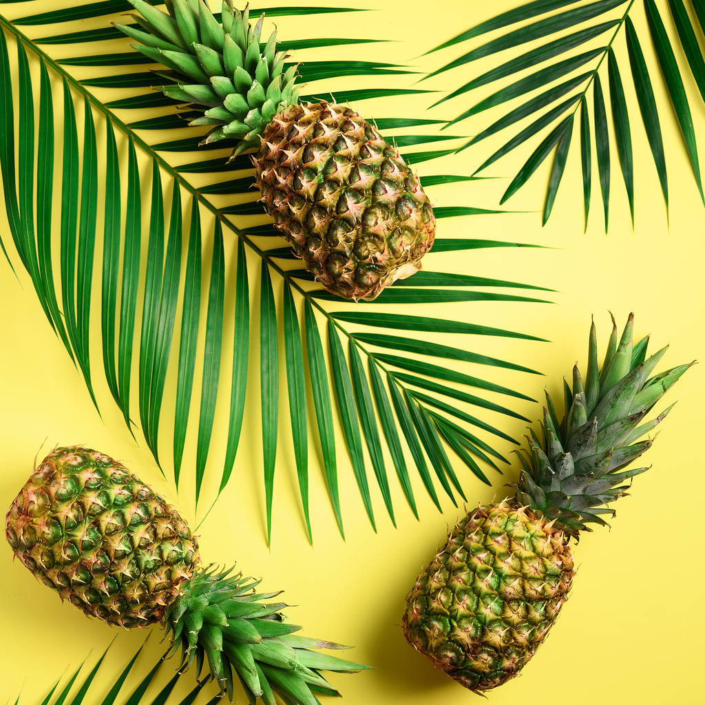 Pineapple and tropical palm leaves on yellow background. Top view. Summer concept. Creative flat lay with copy space. - Photo, Image