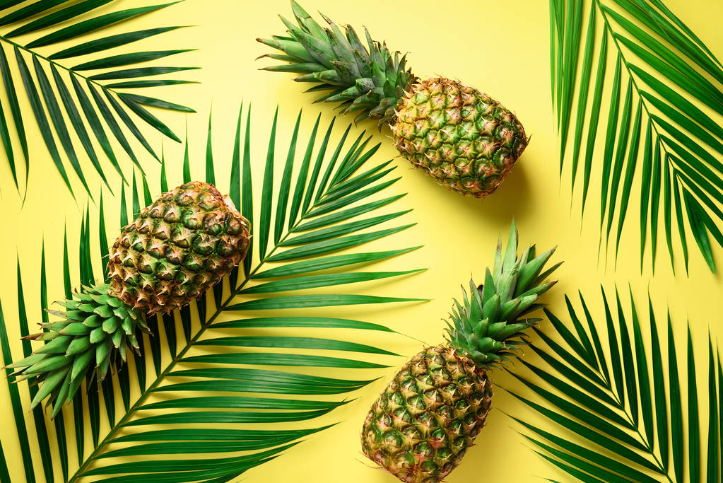 Pineapple and tropical palm leaves on yellow background. Top view. Summer concept. Creative flat lay with copy space. - Photo, Image