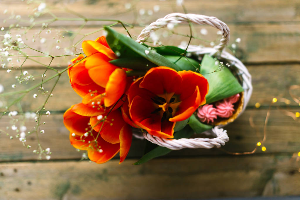 Tulipani in un cesto bianco su uno sfondo di legno con ghirlande sullo sfondo
 - Foto, immagini