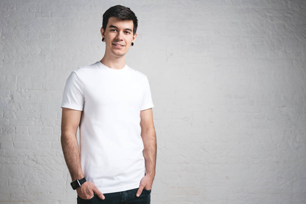 Молодой стильный улыбающийся парень в белой футболке. Студийный портрет, горизонтальный
 - Фото, изображение