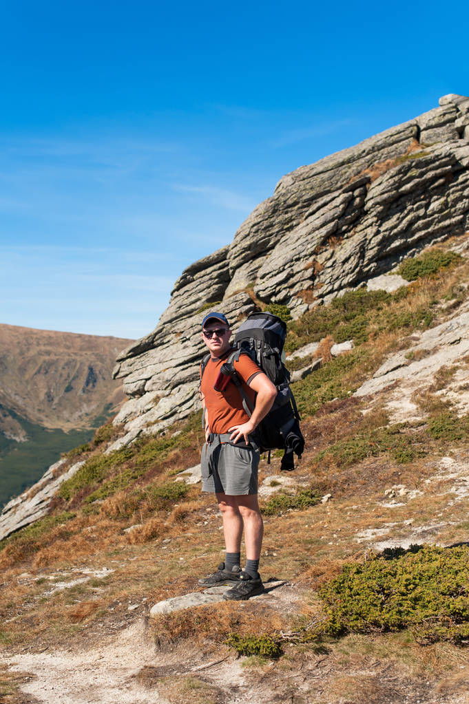 Турист стоїть з рюкзаком на плечах гір
 - Фото, зображення