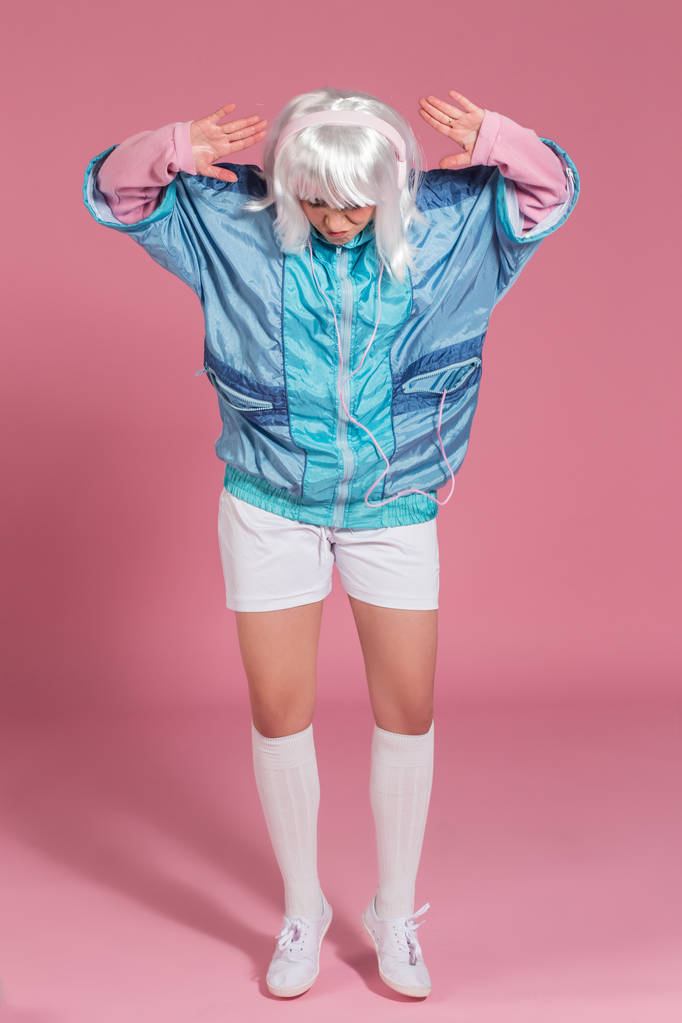 jovem com roupas retro ouvindo música e dançando contra um fundo rosa, estúdio filmado
 - Foto, Imagem