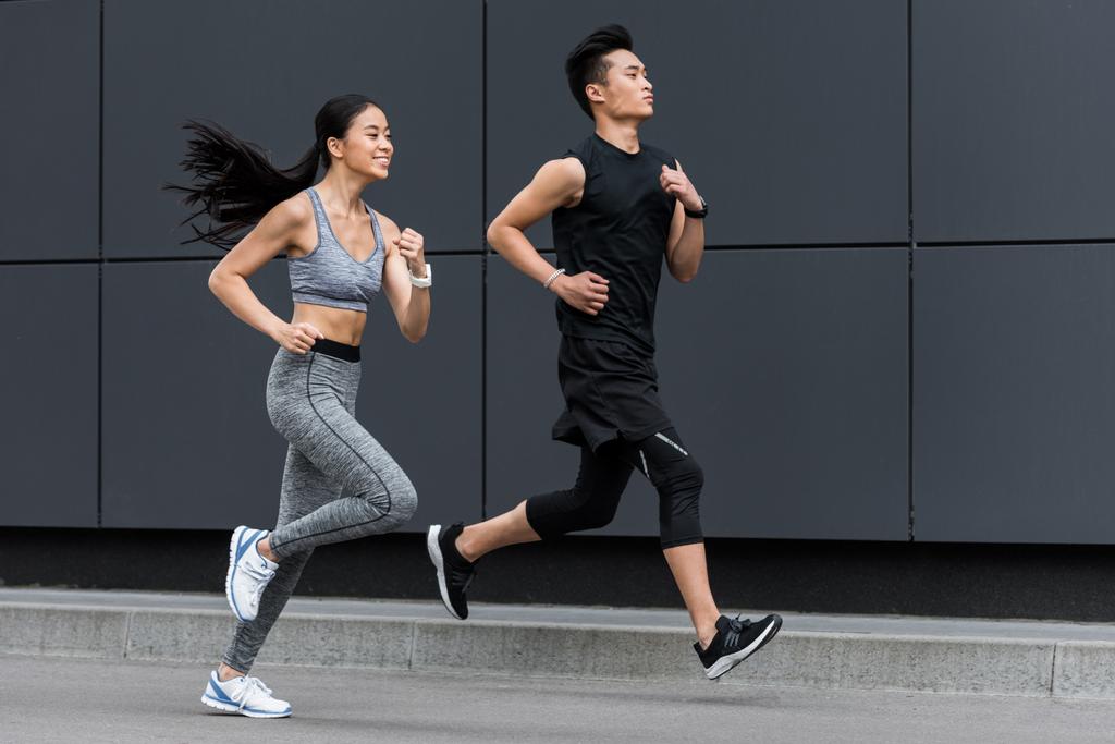 вид сбоку азиатского спортсмена и спортсменки бегущей по городской улице
  - Фото, изображение