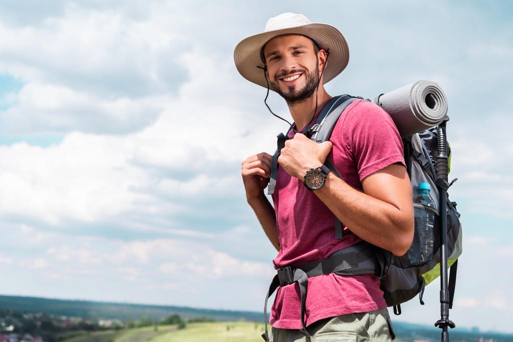mosolygós utas kalapban látszó-on fényképezőgép hátizsák és turisztikai mat - Fotó, kép