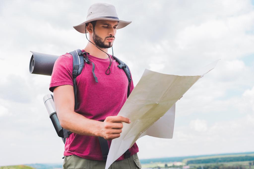 senderista guapo en sombrero con mochila mirando el mapa
 - Foto, imagen