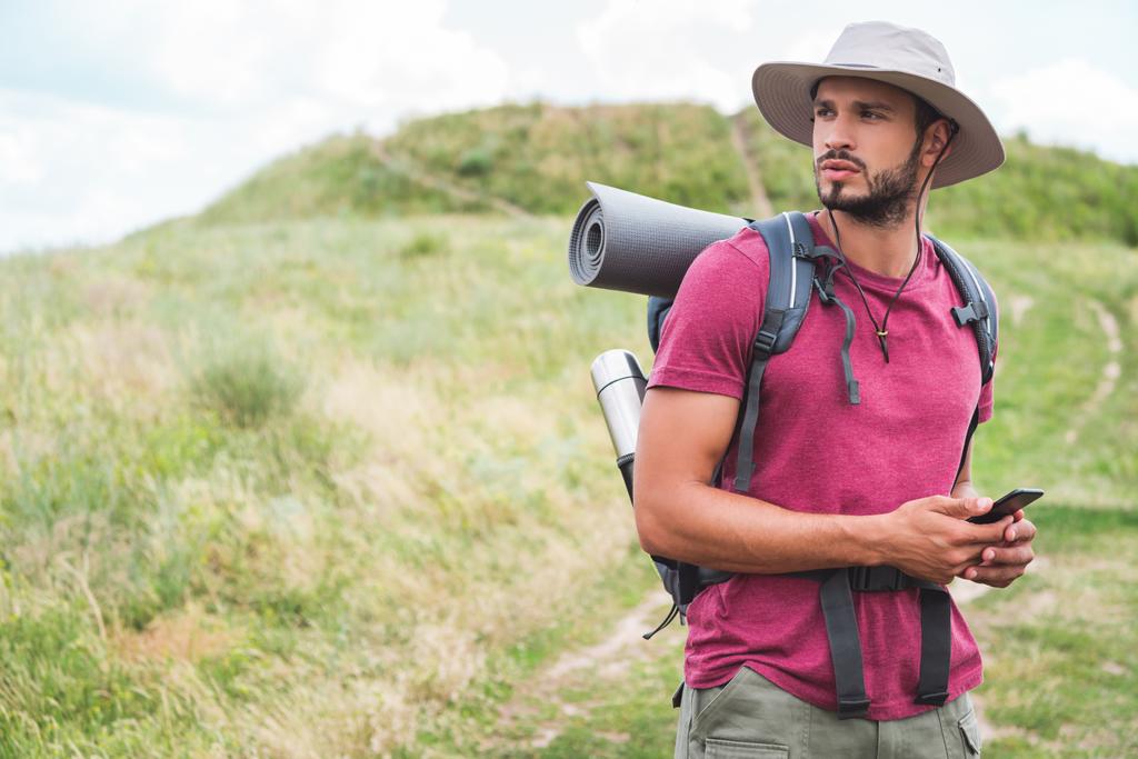 touriste masculin avec sac à dos en utilisant smartphone sur prairie d'été
 - Photo, image
