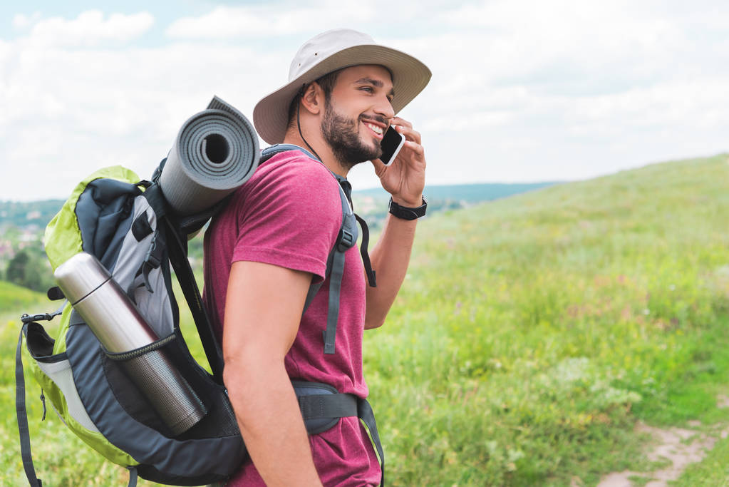 旅行者のバックパックを緑の牧草地でのスマート フォンの話 - 写真・画像