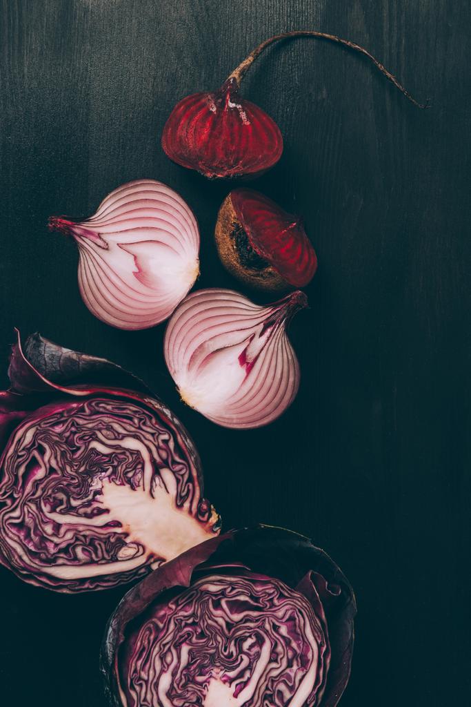 elevated view of halves of beetroot, onion and red cabbage on grey dark table  - Photo, Image