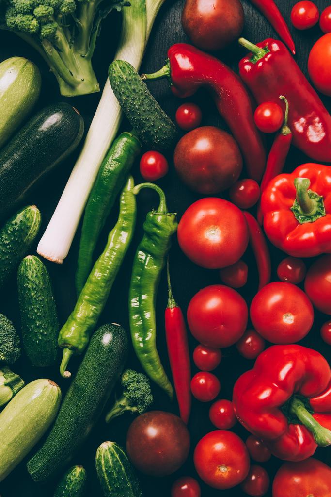 Draufsicht auf rotes und grünes Gemüse auf grauem, dunklem Tisch - Foto, Bild