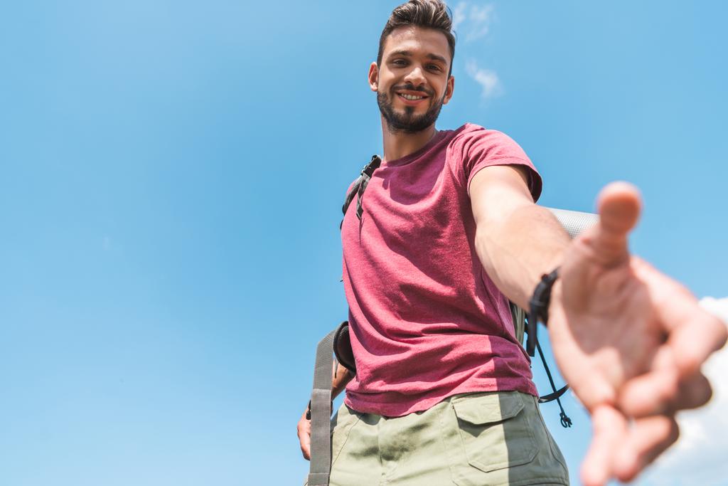 pohja näkymä komea nuori turisti ulottuu käsi, sininen taivas taustalla
 - Valokuva, kuva