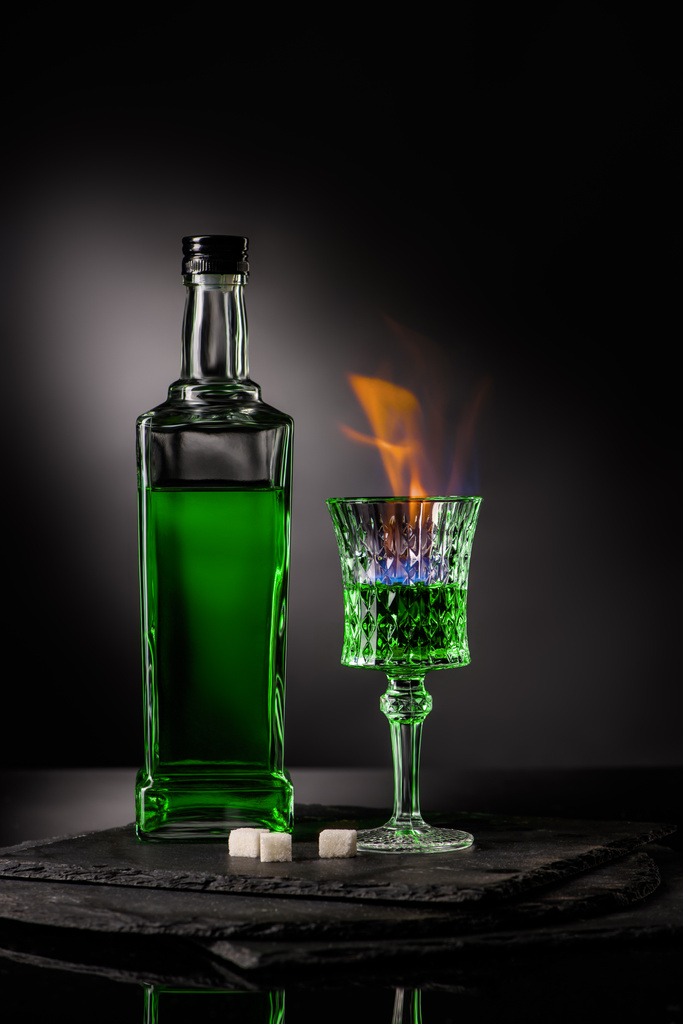 primer plano de botella y vaso de absenta ardiente sobre fondo oscuro
 - Foto, Imagen