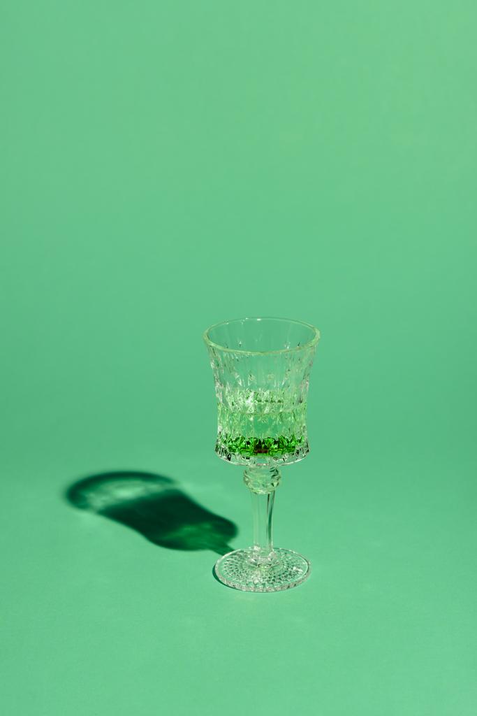 Kristallglas mit Absinthgetränk auf grüner Oberfläche - Foto, Bild