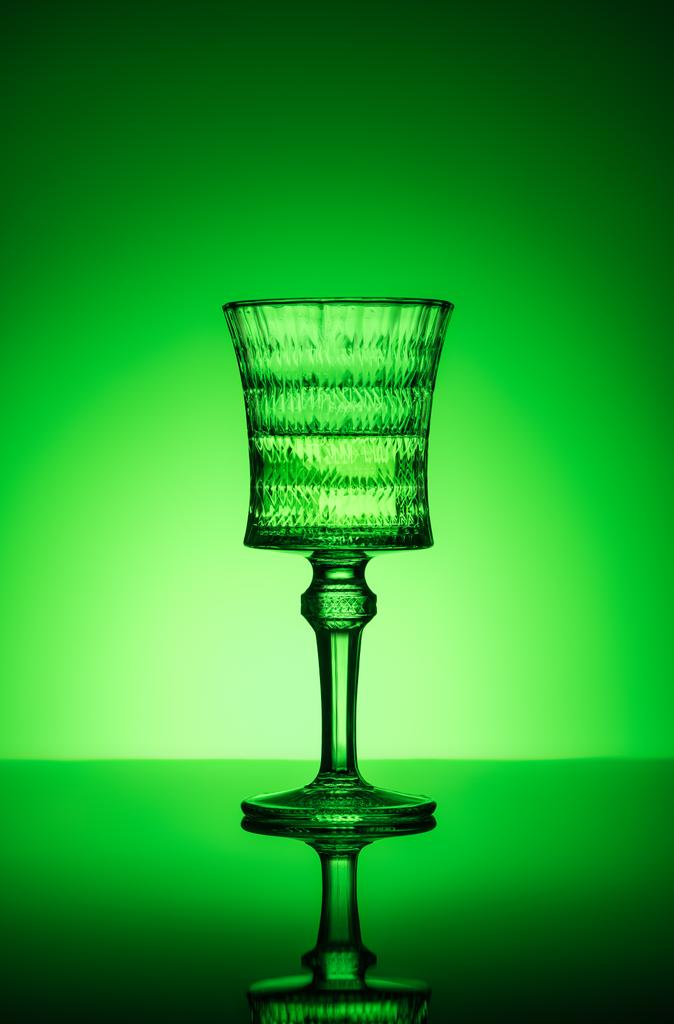 Bleiglas mit Absinth auf reflektierender Oberfläche und dunkelgrünem Hintergrund - Foto, Bild