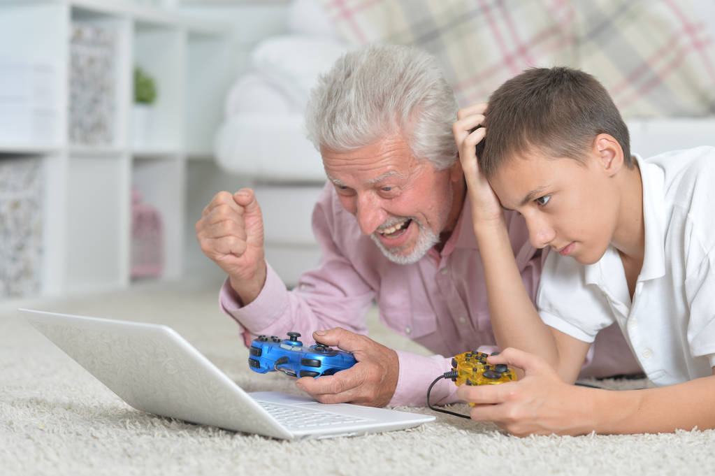 abuelo y nieto tumbado en el suelo y jugando juegos de ordenador portátil
 - Foto, imagen
