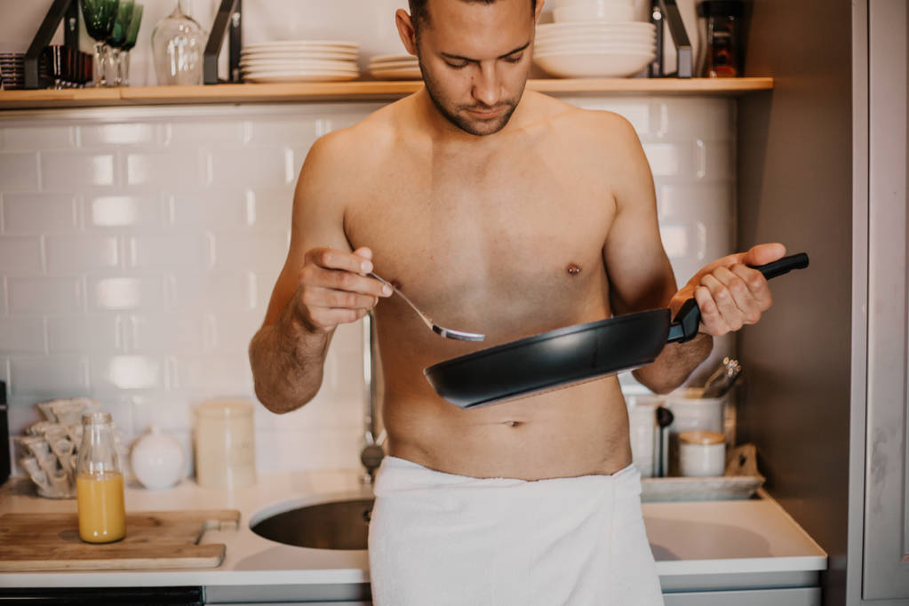 Sexy chef-kok met naakte lichaam koken in de keuken thuis - Foto, afbeelding