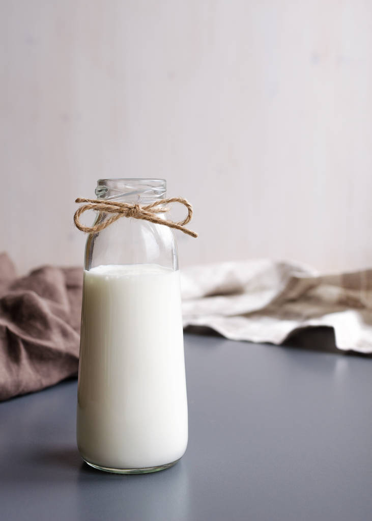 piccola bottiglia di vetro di bevanda di latte fresco su sfondo grigio tavolo con tovagliolo di lino
 - Foto, immagini