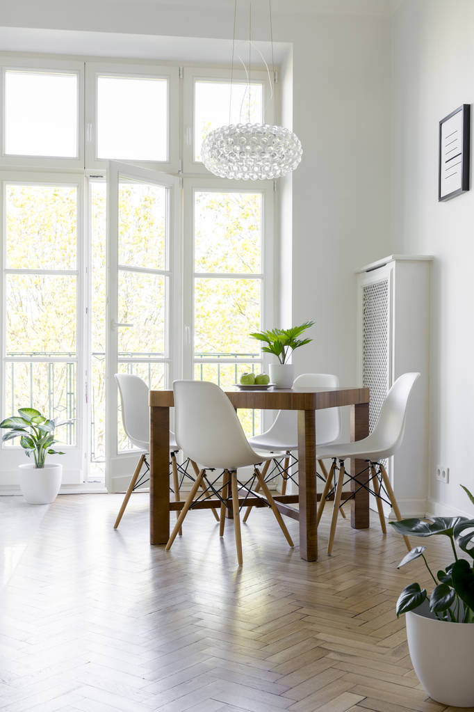 White chairs at table under lamp in bright dining room interior with balcony. Real photo - Photo, Image