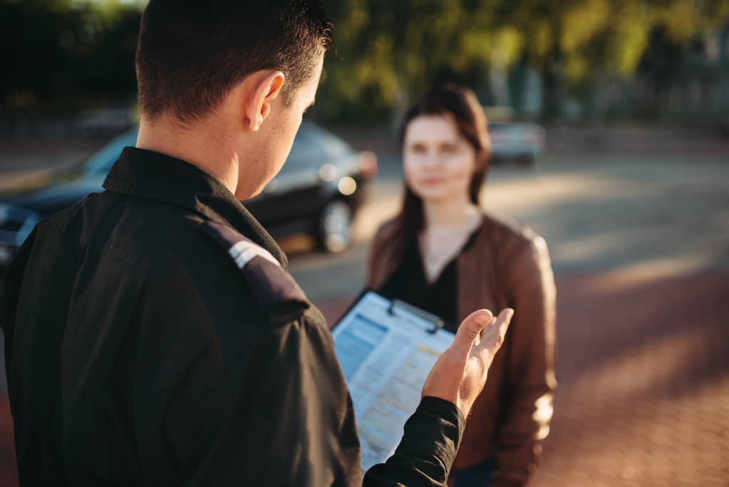 Αξιωματικός της αστυνομίας στην στολή διαβάζει δίκαιο σε γυναίκα οδηγό. Δίκαιο προστασίας, επιθεωρητής κυκλοφορίας αυτοκινήτων, εργασία ελέγχου ασφάλειας - Φωτογραφία, εικόνα