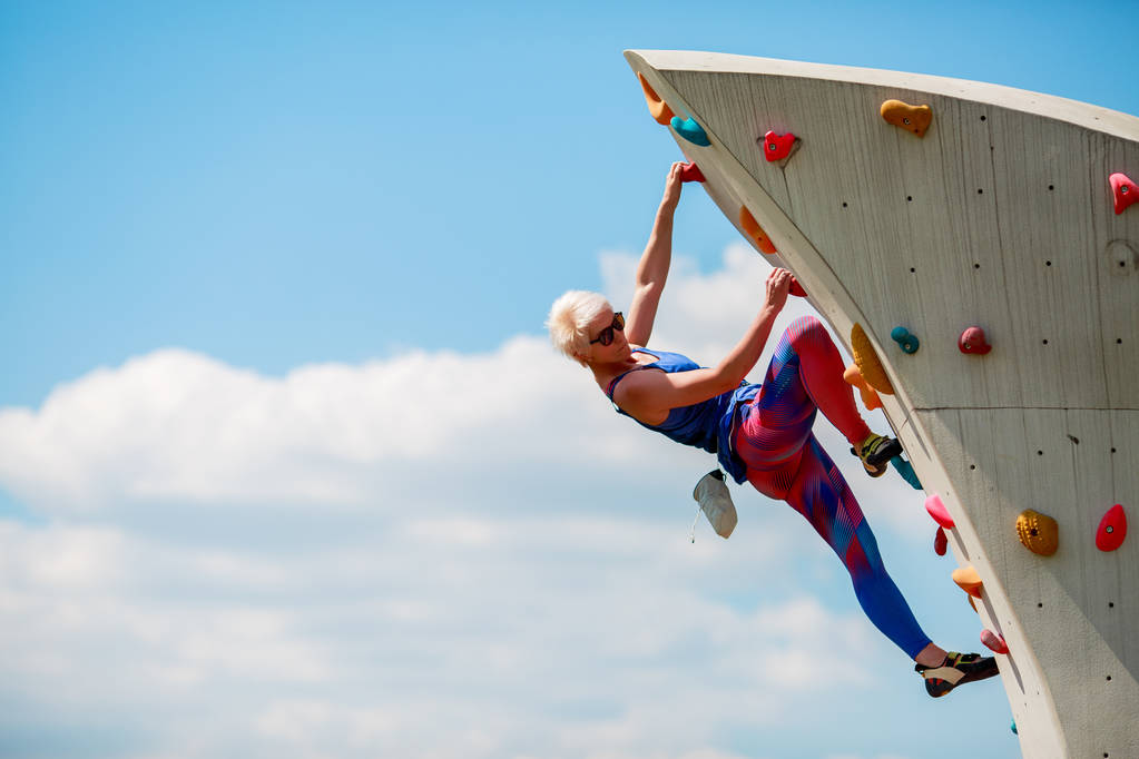 Fotó fiatal sportos nő felkapaszkodott sziklás nyári napon - Fotó, kép