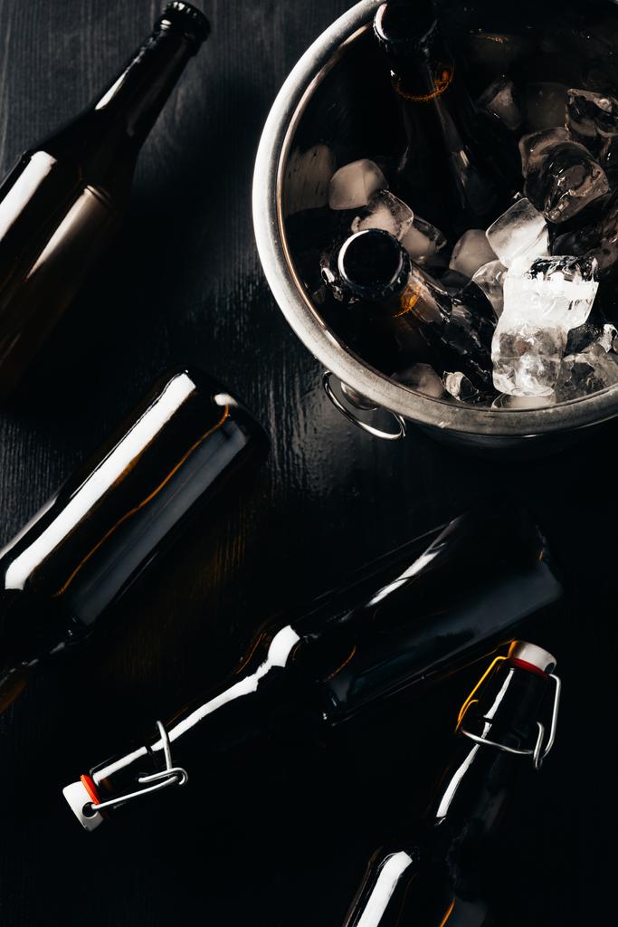 piatta giaceva con secchio, bottiglie di birra e cubetti di ghiaccio disposti su un tavolo scuro
 - Foto, immagini